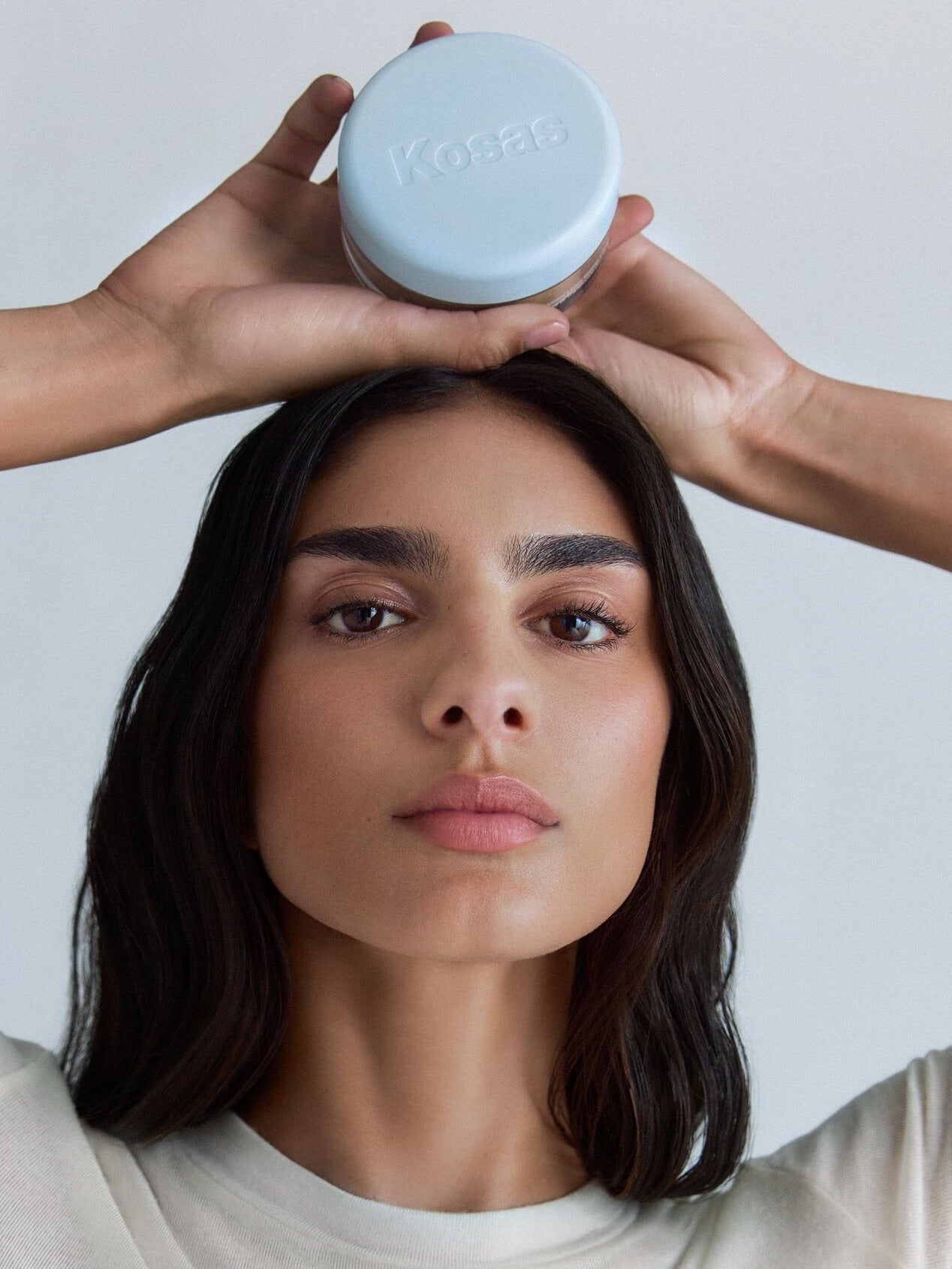 A woman holds a Kosas Cloud Set Loose Powder
